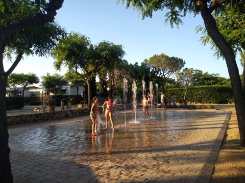 Niños jugando y chapoteando en las fuentes de agua en un día soleado en Camping del Mar, Cataluña, España.