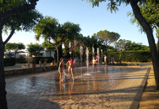 Kinderen spelen en spetteren in waterfonteinen op een zonnige dag in Camping del Mar, Catalonië, Spanje.