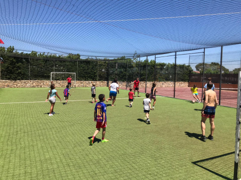 Niños y adultos juegan al fútbol en un campo exterior del Camping del Mar, un parque vacacional en Cataluña.