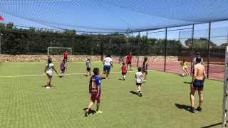 Niños y adultos juegan al fútbol en un campo exterior del Camping del Mar, un parque vacacional en Cataluña.