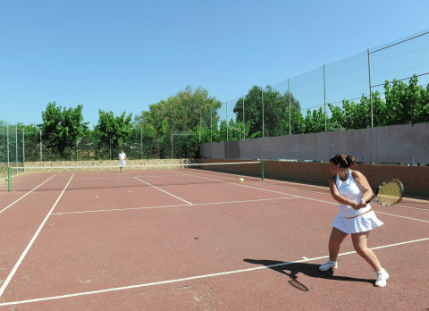 Zwei Personen spielen Tennis auf einem Außenplatz im Camping del Mar Ferienpark in Katalonien, Spanien.
