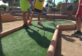 Kinder spielen Minigolf bei sonnigem Wetter im Camping del Mar, einem Ferienpark in Katalonien, Spanien.