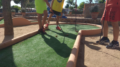 Bambini che giocano a mini golf sotto il sole al Camping del Mar, un villaggio vacanze in Catalogna, Spagna.
