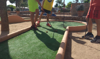 Børn spiller minigolf i solskinsvejr på Camping del Mar, en ferielejrplads i Catalonien, Spanien.