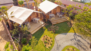 Aerial view of a Glamping Mar safari tent with wooden deck, outdoor seating, and lush green surroundings.