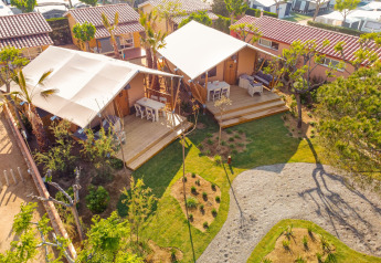 Vista aerea di una tenda safari Glamping Mar con veranda in legno, tavolo da esterno e giardino verde.