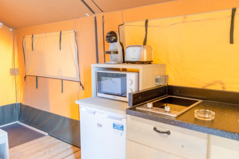 Interno di una tenda safari al Glamping Mar, Camping del Mar, Spagna con cucina, microonde e frigorifero.