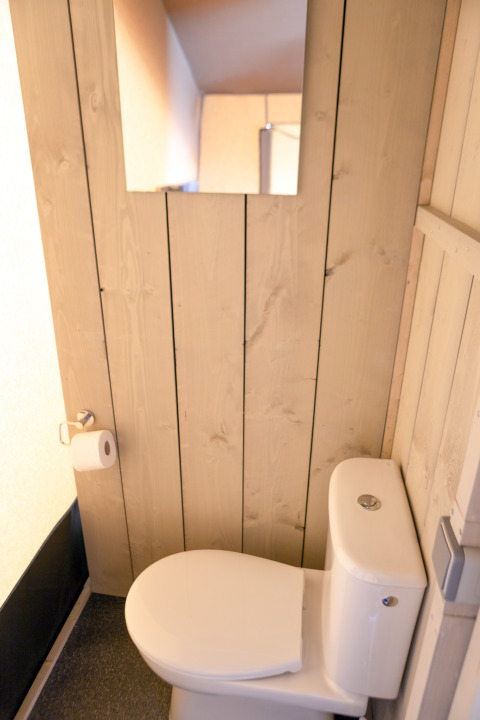 Et moderne toilet i et badeværelse med trævægge og et spejl, fra et safaritelt i Glamping Mar, Spanien.