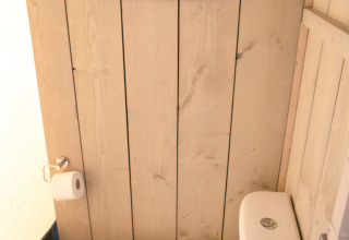 Un moderno WC in un bagno con pareti in legno e specchio, all’interno di una tenda safari a Glamping Mar, Spagna.