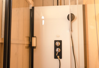 Doccia moderna con porta in vetro e rubinetteria nera in una tenda safari di Glamping Mar, Camping del Mar, Spagna.