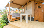 Terraza exterior de una tienda safari en Glamping Mar, Camping del Mar, España, con banco y mesa.
