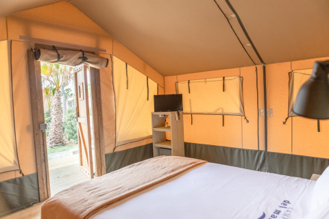 Indvendigt billede af et safari telt på Glamping Mar ved Camping del Mar i Spanien med seng og TV.