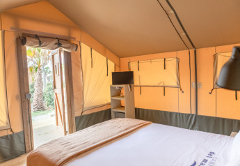 Interior de una tienda safari en Glamping Mar, Camping del Mar en España, mostrando cama y televisor.