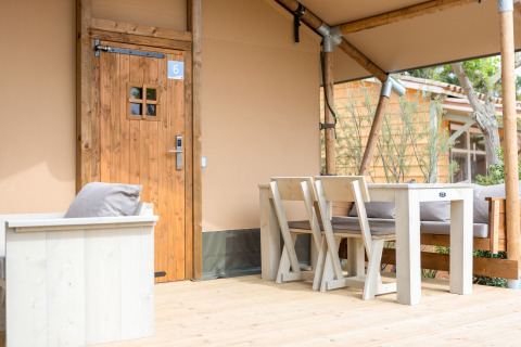 Houten veranda met tafel en stoelen voor safaritent bij Glamping Mar op Camping del Mar, Spanje.