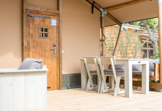 Træveranda med bord og stole foran en safaritelt i Glamping Mar på Camping del Mar, Spanien.