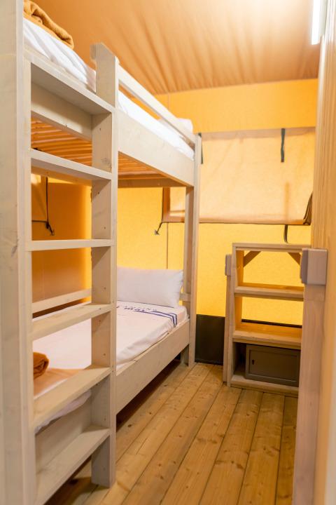 Interior de una tienda safari en Glamping Mar, Camping del Mar, España, con literas y suelo de madera.