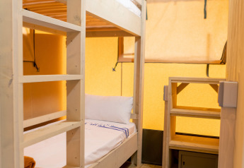 Interior of a safari tent at Glamping Mar, Camping del Mar, Spain, featuring bunk beds and wood flooring.