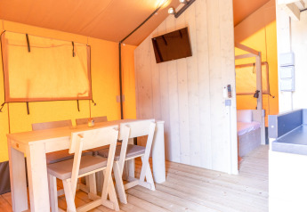 Interior view of a safari tent at Glamping Mar, Camping del Mar, Spain, with table, chairs, and bedroom.