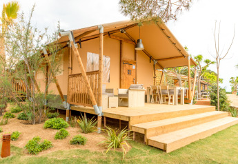 Tenda safari Glamping Mar con veranda in legno e arredo esterno al Camping del Mar in Spagna, tra il verde.