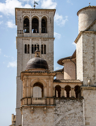 Iglesia histórica con campanario y cúpula cerca de Bevagna, Umbría, Italia, bajo un cielo azul claro.