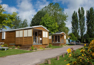 Chalets omgeven door bomen op Camping Seasonova Haliotis, een vakantiepark in Normandië, Frankrijk.