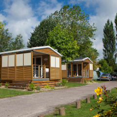 Bungalows rodeados de árboles en Camping Seasonova Haliotis, un parque vacacional en Normandía, Francia.