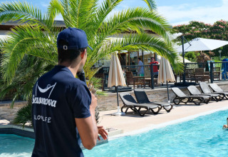 Mann im Seasonova-Shirt am Pool im Camping Seasonova Haliotis, Ferienpark in der Normandie, Frankreich.