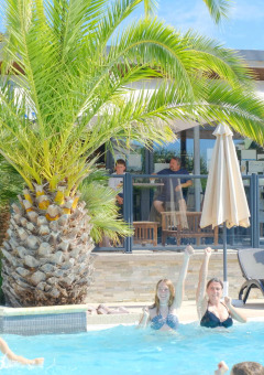 Huéspedes disfrutan de la piscina y el sol en Camping Seasonova Haliotis en Normandía, Francia.