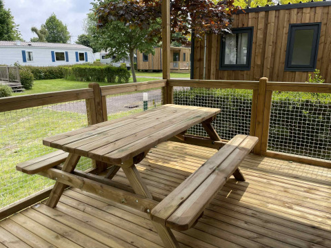 Holztisch und Bänke auf einer Terrasse im Camping Seasonova Haliotis Ferienpark in der Normandie, Frankreich.