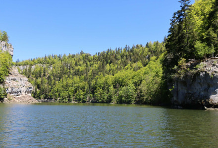 Río tranquilo rodeado de frondosos bosques y acantilados rocosos cerca de Les Brenets en Neuchâtel, Suiza.