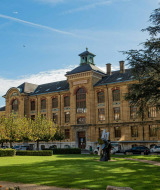 Majestuoso edificio histórico rodeado de un parque verde y árboles en Les Brenets, Neuchâtel, Suiza.