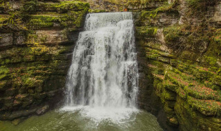 Cascada rodeada de acantilados cubiertos de musgo cerca de Les Brenets, Neuchâtel, Suiza, en otoño.
