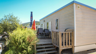 Mobilhome O'Hara met terras en ligstoelen op Camping Lac des Brenets, Zwitserland, op een zonnige dag