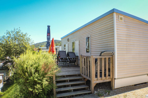 Mobilheim O'Hara mit Terrasse und Liegestühlen auf Camping Lac des Brenets, Schweiz, bei Sonnenschein