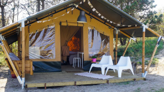 Tienda safari Lodge Escape con terraza de madera, dos sillas blancas y naturaleza alrededor.