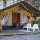 Safari telt Lodge Escape med terrasse, to hvide stole og naturskøn udsigt blandt træerne.