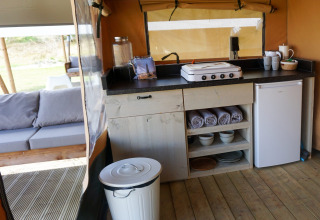 Zona de cocina en tienda safari de Lodge Escape, Little Canvas Escape, Países Bajos, con frigorífico.