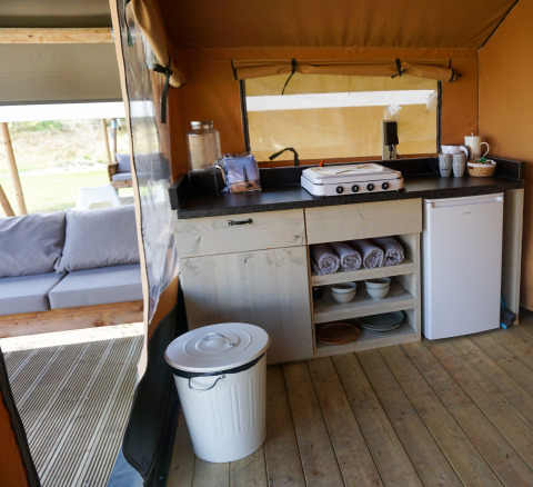 Küchenbereich in einem Safarizelt der Lodge Escape bei Little Canvas Escape, Niederlande, mit Sofa.