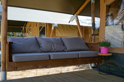 Rincón de relax en una tienda safari con sofá gris en Lodge Escape, Little Canvas Escape, Países Bajos.