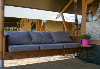 Rincón de relax en una tienda safari con sofá gris en Lodge Escape, Little Canvas Escape, Países Bajos.