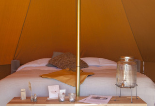 Intérieur cosy d'un tipi Bell Escape à Little Canvas Escape aux Pays-Bas avec lit et décoration soignée.