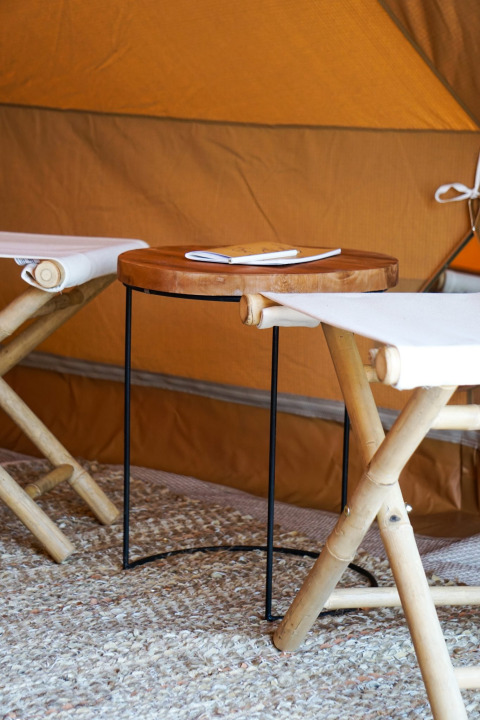 Interior de una tienda tipi Bell Escape en Little Canvas Escape, Países Bajos, con sillas de bambú y mesa de madera.