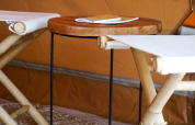 Interior de una tienda tipi Bell Escape en Little Canvas Escape, Países Bajos, con sillas de bambú y mesa de madera.