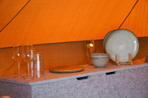 Vajilla y copas dentro del tipi Bell Escape en Little Canvas Escape, Países Bajos, sobre una mesa.