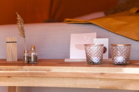 Primer plano de una mesa de madera con jarrones de cristal, tarjetas y velas en la tienda Bell Escape.