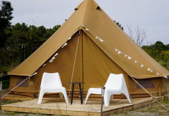 Foto de la tienda tipi Bell Escape con dos sillas blancas en Little Canvas Escape, Países Bajos.