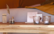 Frascos decorativos, velas y pasto seco sobre mesa de madera en la tienda Bell Escape Family en Países Bajos.