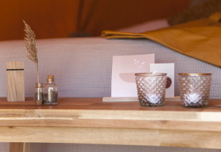 Frascos decorativos, velas y pasto seco sobre mesa de madera en la tienda Bell Escape Family en Países Bajos.