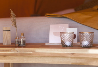 Pots décoratifs, bougies et herbe séchée sur une table en bois dans la tente Bell Escape Family.