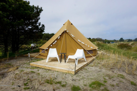 Una tienda tipi Bell Escape Family en Little Canvas Escape, Países Bajos, con dos sillas blancas delante.